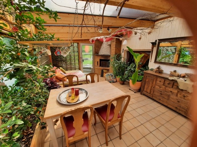 Großer Wintergarten mit offenem Kamin sowie Spiegel und Sideboard