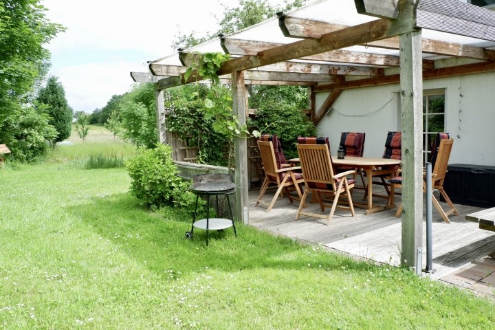 Überdachte Terrasse mit Grill und Gartenmöbeln