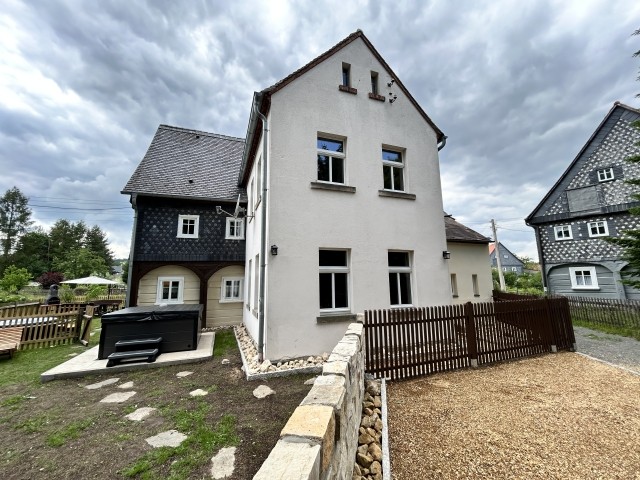 Blick vom Parkplatz auf Haus und den Garten der Fewo Ornella