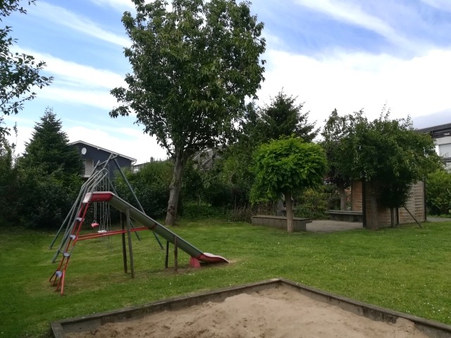 Blick aus dem Gemeinschaftsgarten mit Spielplatz und Grillecke