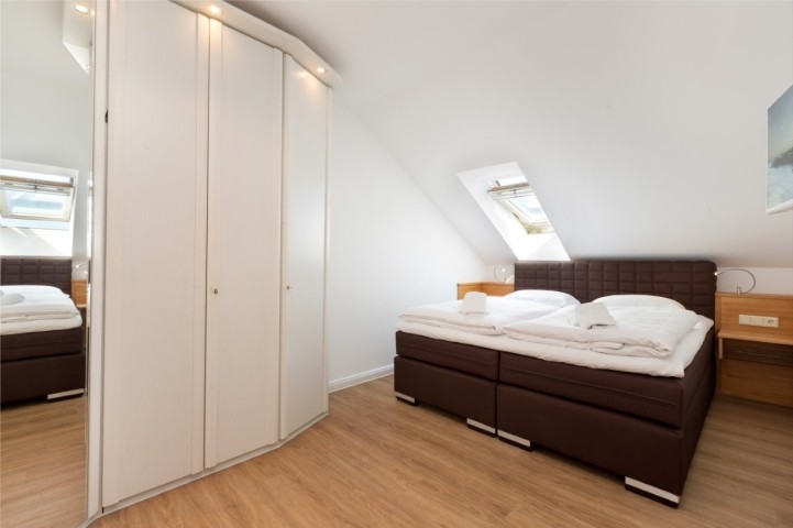 Schlafzimmer mit TV und großem Kleiderschrank.