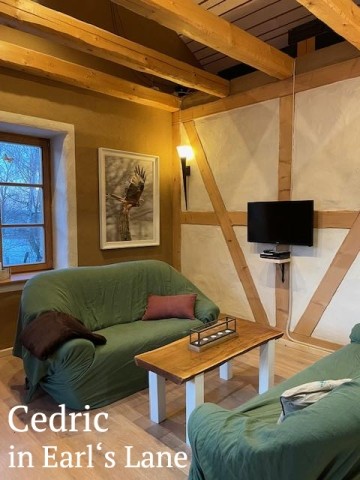 Wohnzimmer mit Holzmöbeln, gemütlicher Beleuchtung und hellem Lehmfachwerk