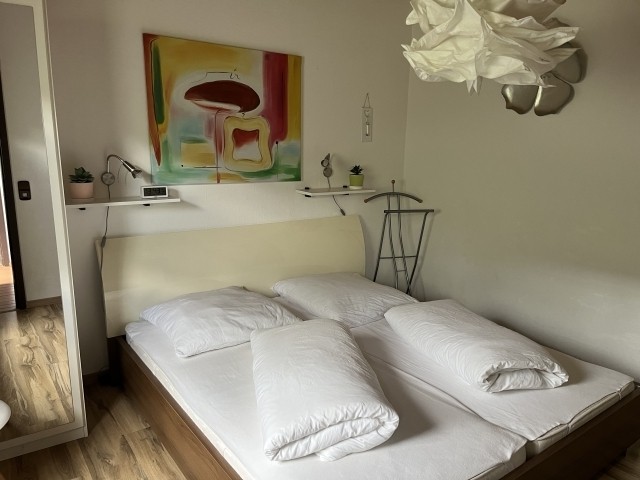 Schlafzimmer 1 mit Doppelbett, Schrank und Sessel