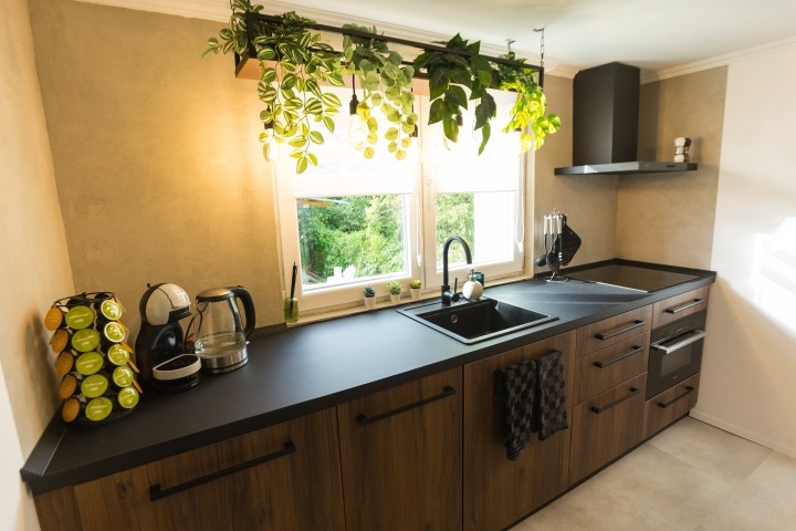 Eine helle, moderne Küche mit kühler Optik, warmen Holztönen und grünen Details. Alles ist vorhanden für ein entspanntes Frühstück oder ein selbstgekochtes Abendessen mit Blick in den Garten.