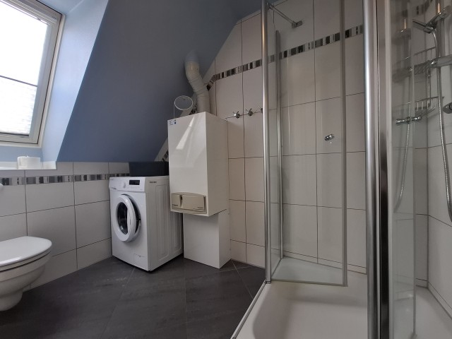 Badezimmer mit Dusche und Waschmaschine