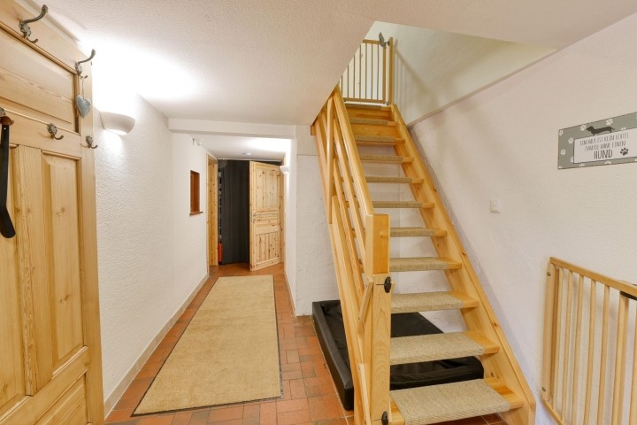 Flur mit offener Holztreppe und Teppichstufen ins OG