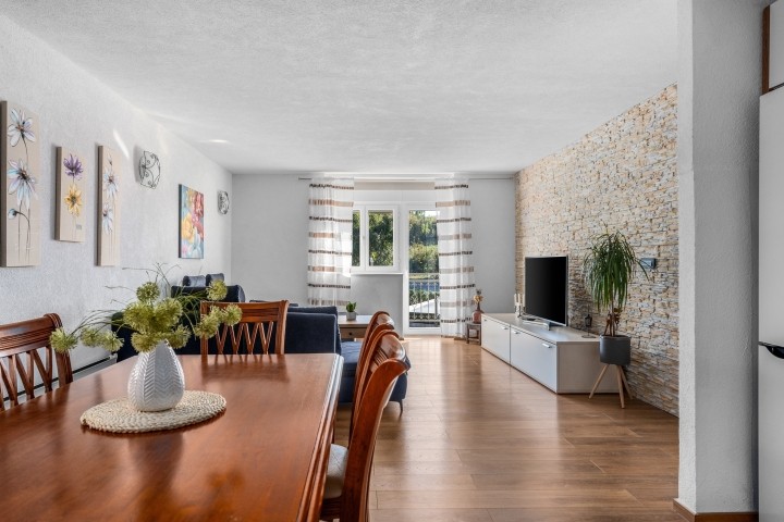 Esstisch, Wohnzimmer mit sehr bequemem Sofa, einem Fernseher und einem Balkon mit Blick auf den Pool