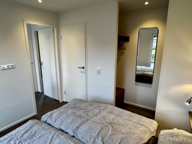 Offen gestalteter Kleiderschrank und Zugang zum Bad