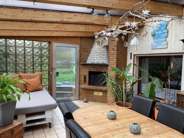 Wintergarten mit offenem Kamin und gemütlicher Sitzecke.
