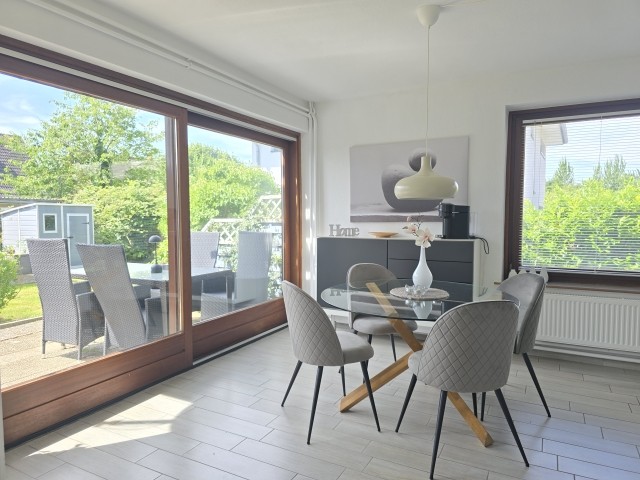 Essbereich mit großer Schiebetür zur Terrasse und hoch eingezäuntem Garten