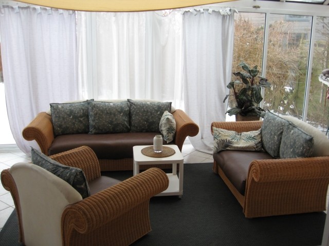 Der geräumige Wintergarten ist mit einer eleganten Korbmöbelgarnitur ausgestattet. Geniessen Sie auch gemütliche Abende vor dem offenem Kamin mit gleichzeitigem Blick über die Ostsee. Einmalig.