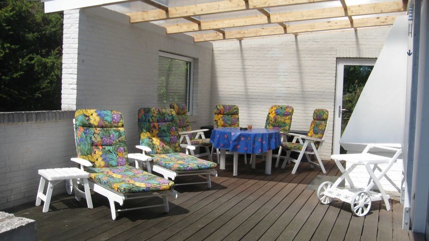 Die großzügige Terrasse mit Holzboden lädt zum gemütlichen Verweilen ein. Die Hälfte ist überdacht und bietet von daher bei jedem Wetter ein Sitzvergnügen. Der Außenkamin macht die Sache perfekt.